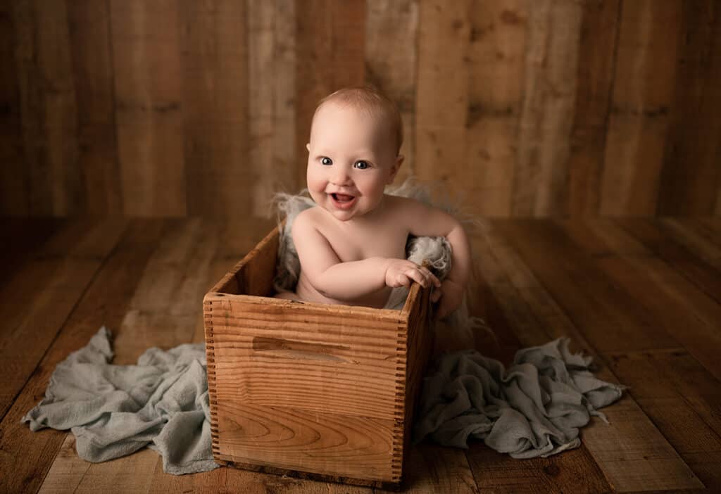 newton ks milestone photographer baby in box smiling