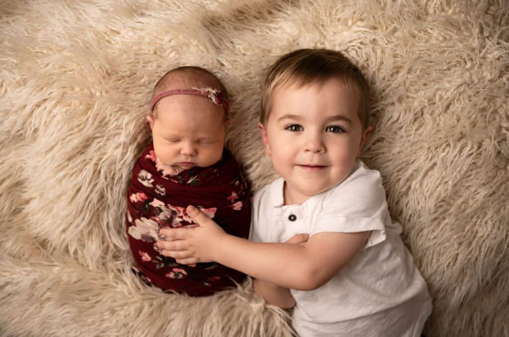 big brother holds new baby sister in a newborn photo session