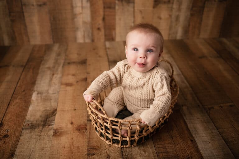 newton ks milestone photographer six months sitter in basket smiling