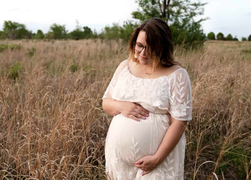 mother holds baby belly in maternity photos