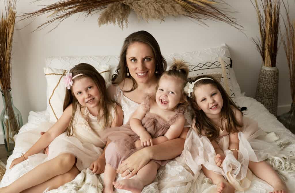 mother poses with her daughters on a boho bed