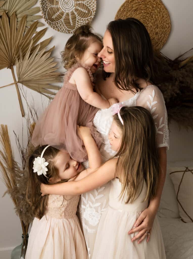 three girls hug their mother in a boho studio