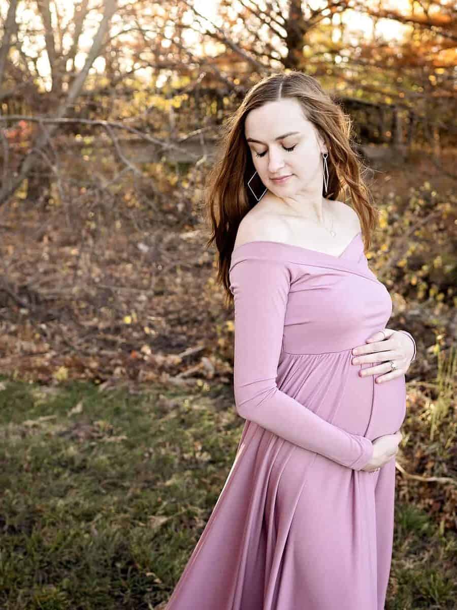 expecting mother breathes in and holds her baby bump